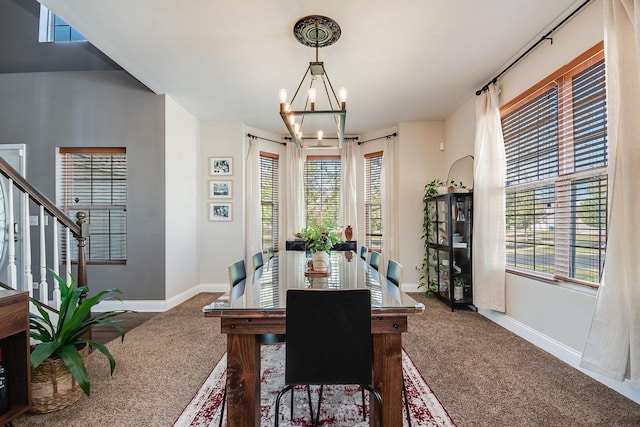 dining area with a chandelier, carpet flooring, and baseboards