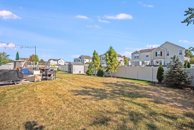 view of yard featuring a shed, a residential view, fence, and an outbuilding