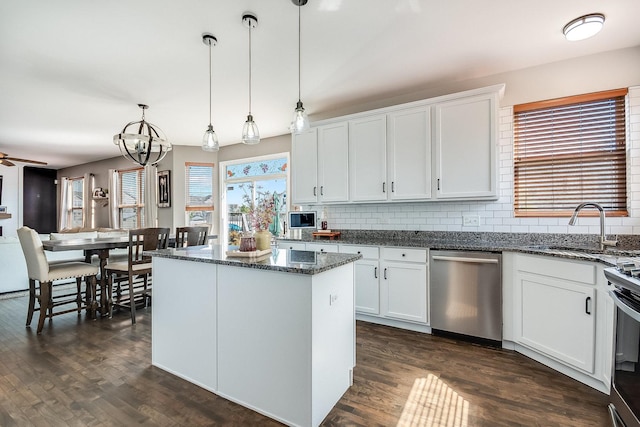 kitchen with tasteful backsplash, dark wood-style floors, appliances with stainless steel finishes, a center island, and a sink