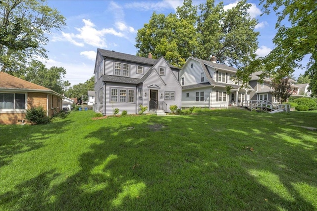 rear view of property featuring entry steps, a lawn, a chimney, and a gambrel roof