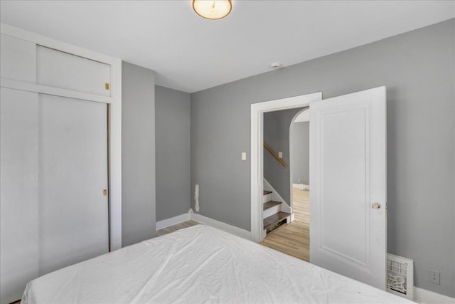 bedroom with baseboards, a closet, visible vents, and wood finished floors