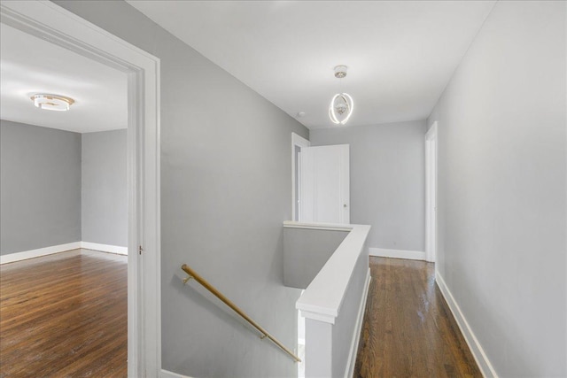 hall with dark wood finished floors, an upstairs landing, and baseboards