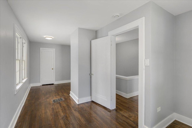 interior space featuring dark wood-type flooring, visible vents, and baseboards