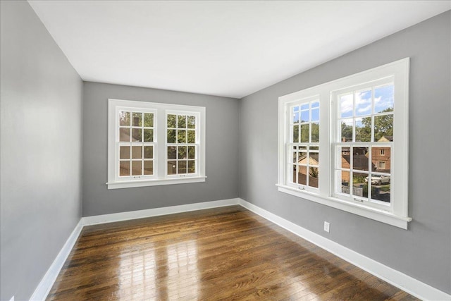 empty room featuring baseboards and dark wood finished floors