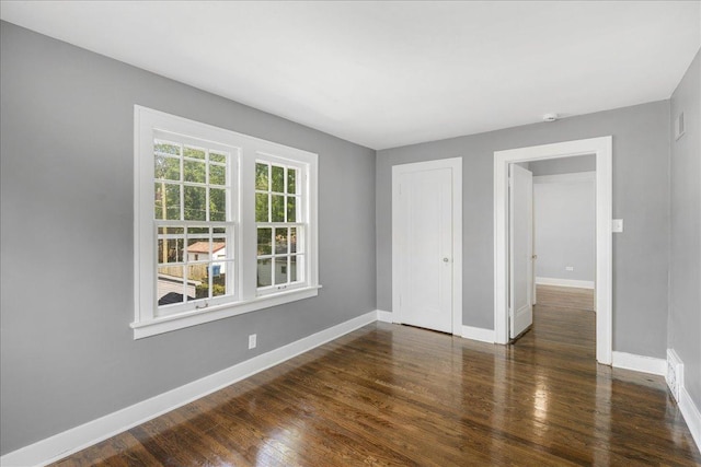 spare room with baseboards and wood finished floors