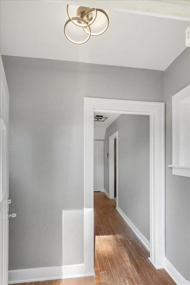 corridor with baseboards and wood finished floors