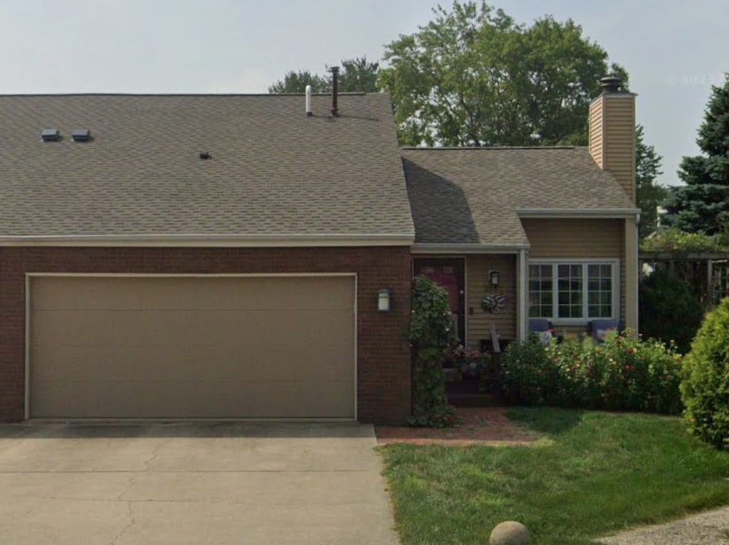 view of front of property with an attached garage, a front yard, concrete driveway, and brick siding