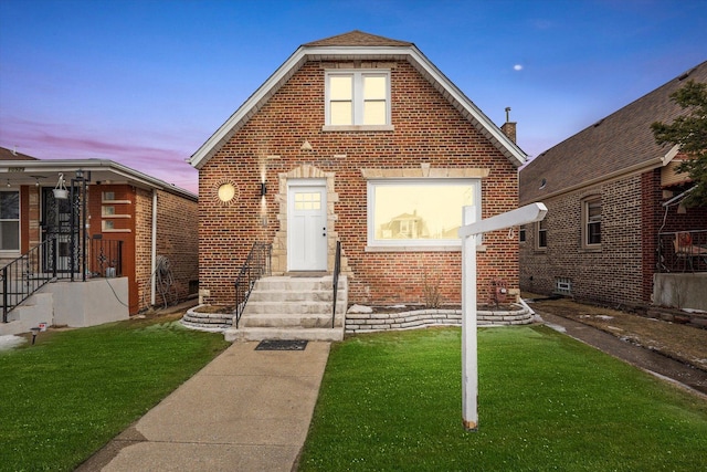 view of front of home featuring brick siding and a lawn