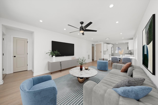 living area with baseboards, light wood finished floors, a ceiling fan, and recessed lighting