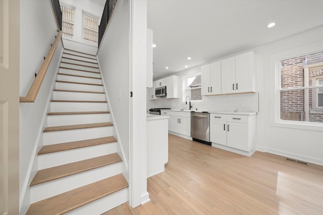 stairway featuring wood finished floors, visible vents, and recessed lighting