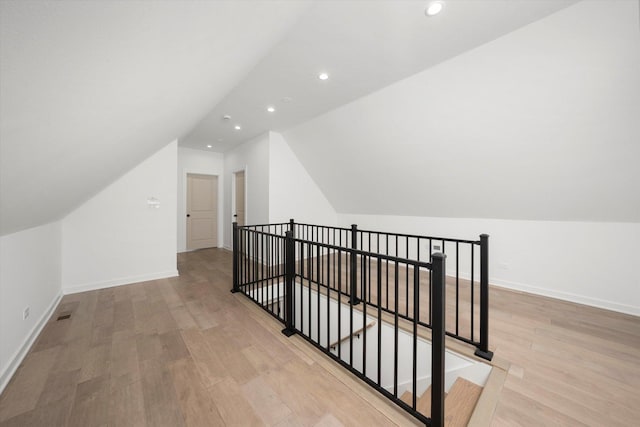 bonus room with baseboards, lofted ceiling, and light wood-style floors