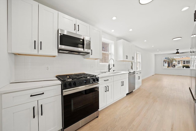 kitchen with light countertops, appliances with stainless steel finishes, light wood-type flooring, decorative backsplash, and plenty of natural light