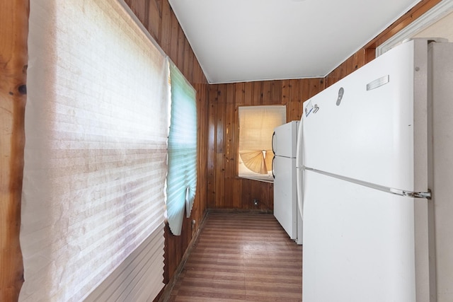 kitchen with wood finished floors, freestanding refrigerator, and wooden walls