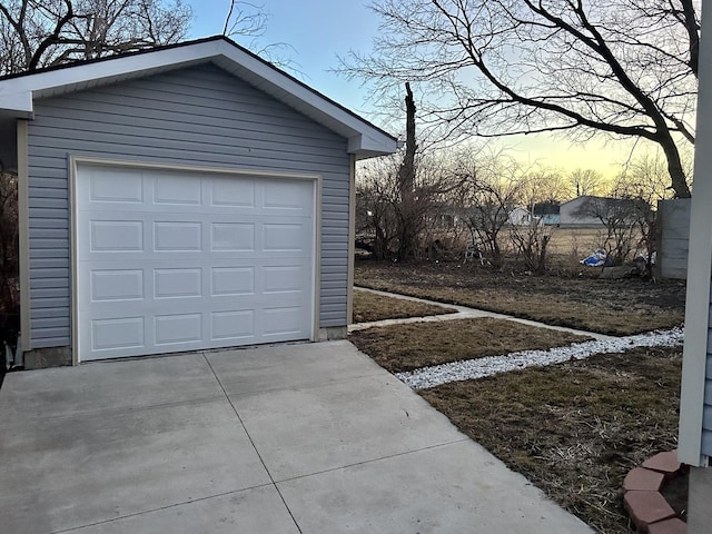 garage at dusk featuring concrete driveway