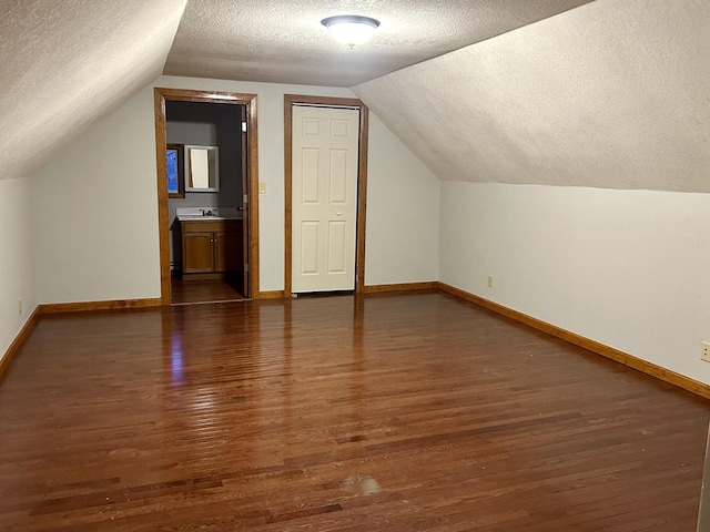 bonus room featuring lofted ceiling, a textured ceiling, baseboards, and wood finished floors