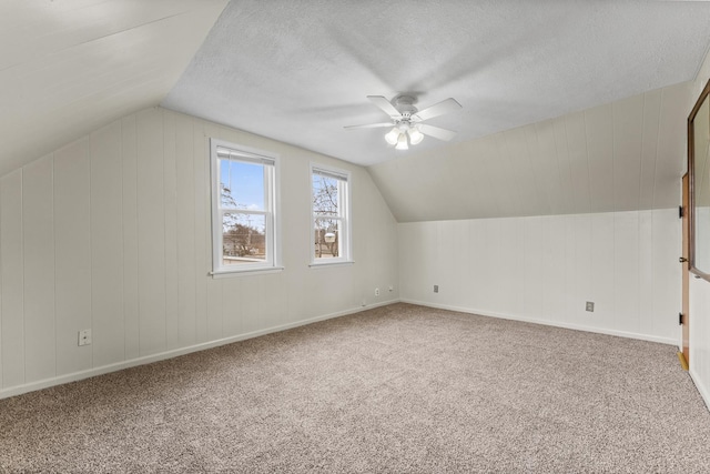 bonus room with a textured ceiling, vaulted ceiling, carpet flooring, and a ceiling fan