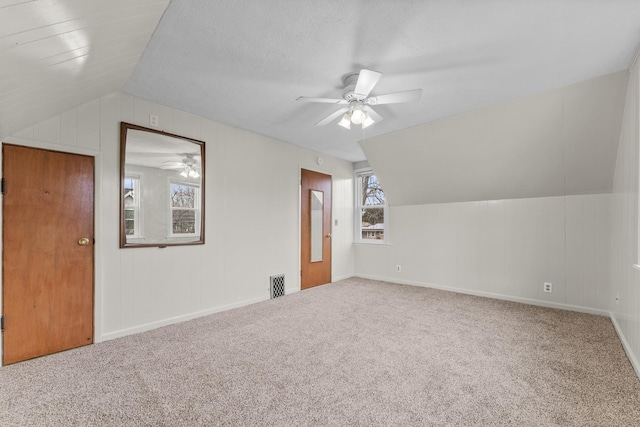 additional living space with visible vents, vaulted ceiling, carpet flooring, and ceiling fan