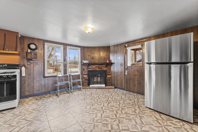 kitchen with a brick fireplace, range with gas cooktop, a wealth of natural light, and freestanding refrigerator