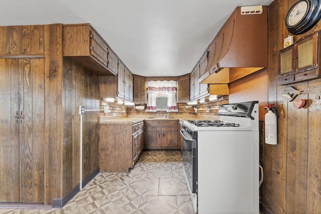 kitchen with light floors, white gas range oven, light countertops, and brown cabinets