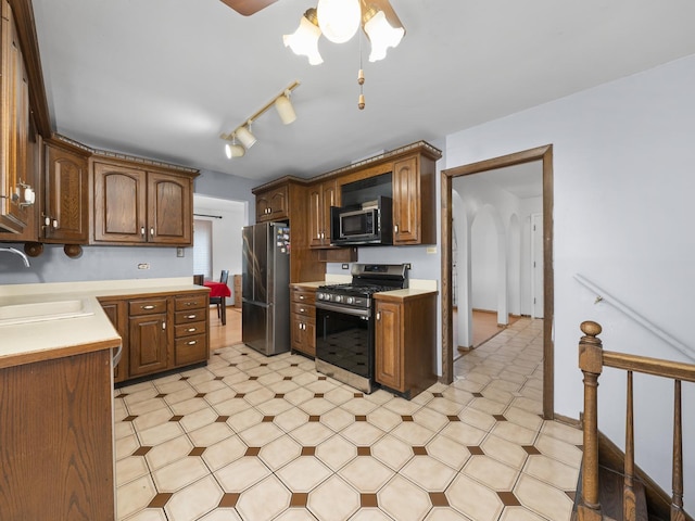 kitchen with stainless steel appliances, light countertops, a sink, and light floors