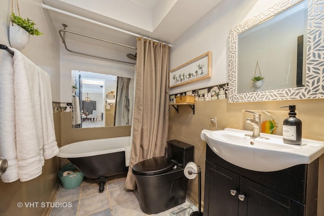 bathroom with a freestanding tub, toilet, and vanity