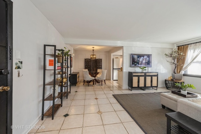 living area with baseboards, a notable chandelier, and light tile patterned flooring