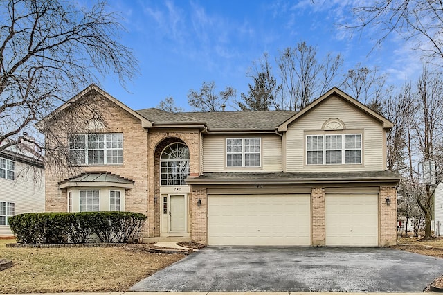 traditional-style home with an attached garage, roof with shingles, aphalt driveway, and brick siding