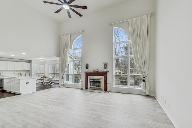 unfurnished living room with a healthy amount of sunlight, ceiling fan, and a high ceiling