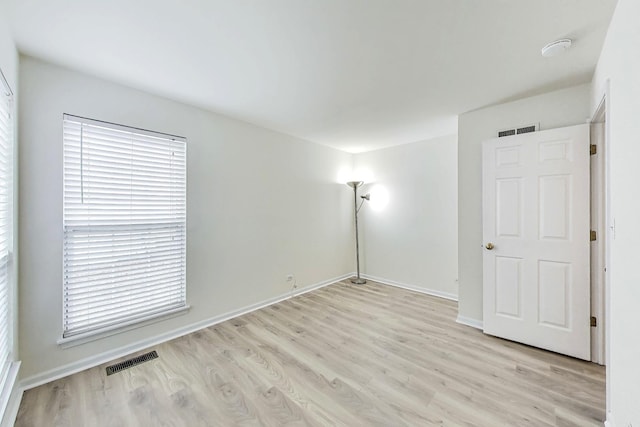 empty room featuring light wood finished floors, baseboards, and visible vents