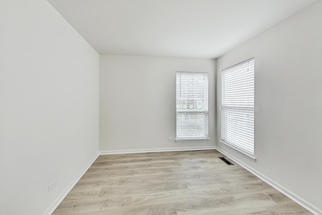 empty room featuring light wood-type flooring, visible vents, and a healthy amount of sunlight