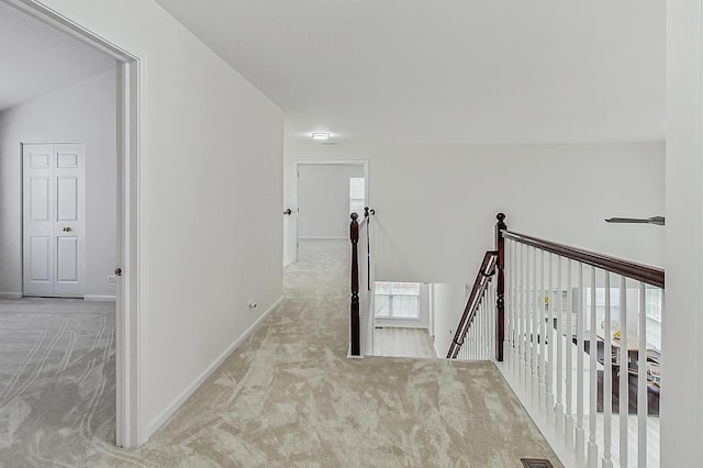 hallway with carpet, baseboards, a wealth of natural light, and an upstairs landing