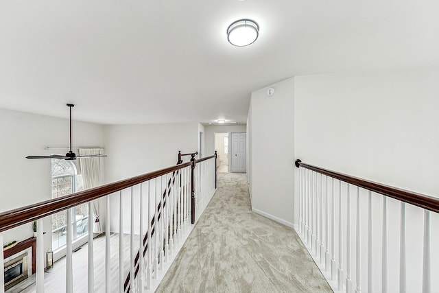 hallway featuring carpet, baseboards, and an upstairs landing