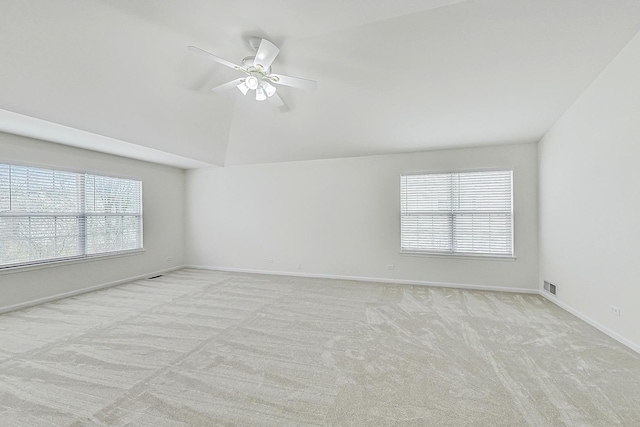 empty room with light carpet, plenty of natural light, visible vents, and vaulted ceiling