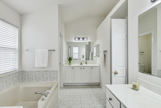 bathroom featuring lofted ceiling, tile patterned flooring, vanity, and a bath