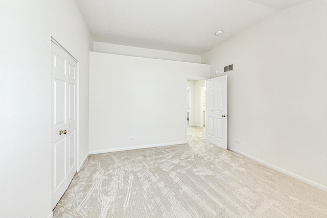 unfurnished bedroom featuring light colored carpet, visible vents, vaulted ceiling, and baseboards