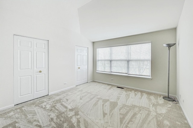 unfurnished bedroom with multiple closets, visible vents, carpet flooring, vaulted ceiling, and baseboards