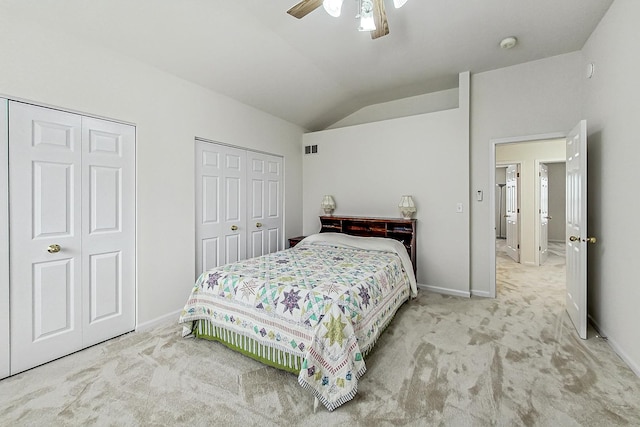 carpeted bedroom featuring lofted ceiling, baseboards, visible vents, and two closets