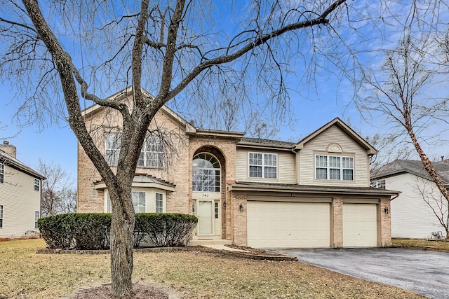 traditional home featuring aphalt driveway, brick siding, and a garage