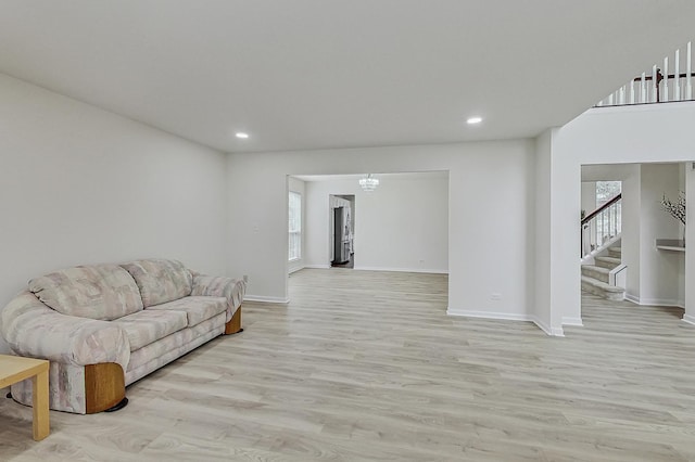 living area with plenty of natural light, stairway, and light wood-type flooring