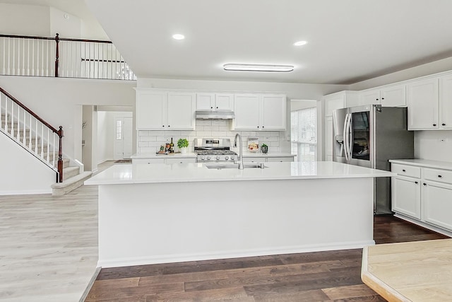 kitchen with dark wood-style floors, stainless steel appliances, light countertops, a sink, and under cabinet range hood