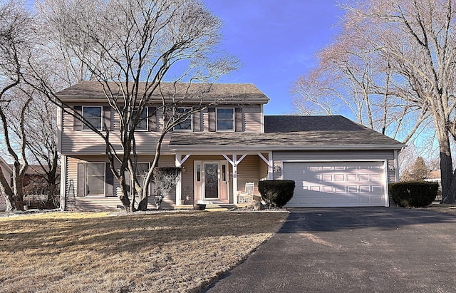 colonial home featuring a garage, aphalt driveway, and a front yard