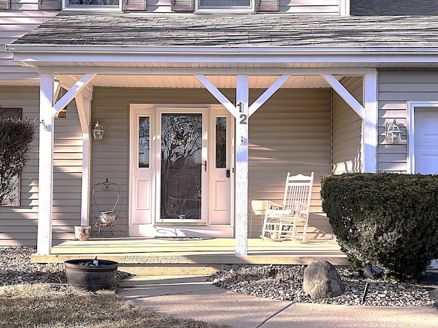 doorway to property with covered porch and roof with shingles