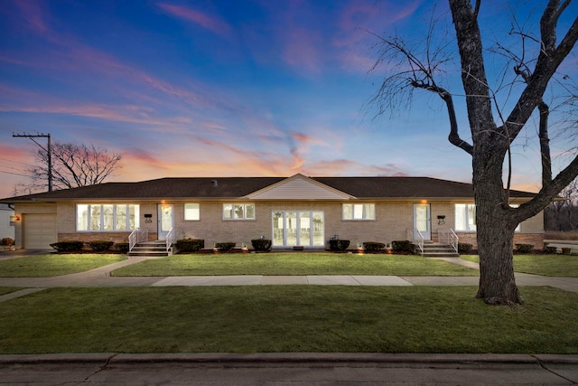 ranch-style house with an attached garage, brick siding, and a yard