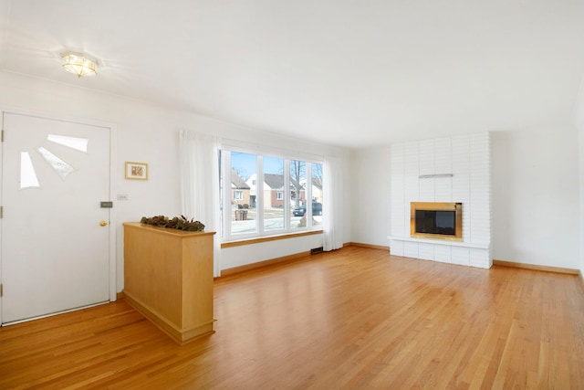 unfurnished living room featuring baseboards, a fireplace, and light wood finished floors