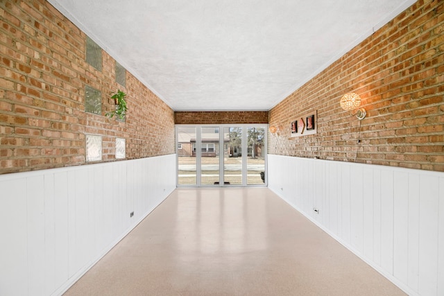 2547 2nd Ave, North Riverside, IL 60546 - unfurnished room featuring brick wall, a wainscoted wall, and a textured ceiling