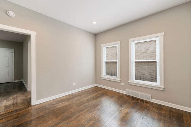 spare room with baseboards, visible vents, and dark wood-type flooring