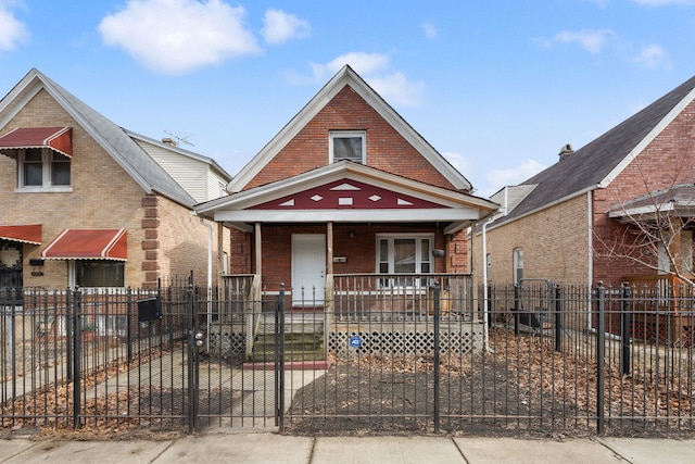 view of front of property with a porch, a fenced front yard, a gate, and brick siding