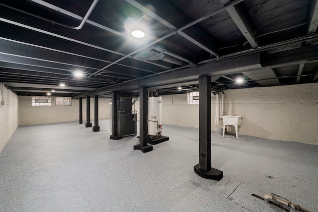 basement featuring heating unit, a sink, and gas water heater