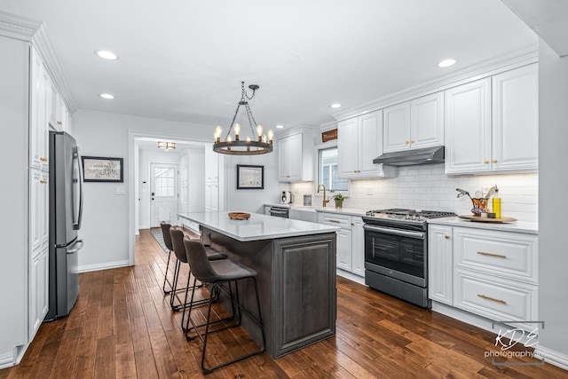 kitchen featuring a center island, light countertops, appliances with stainless steel finishes, white cabinetry, and under cabinet range hood