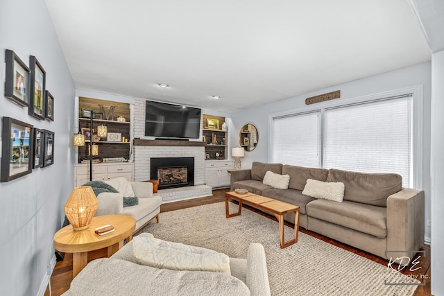 living area with built in features, a fireplace, and wood finished floors